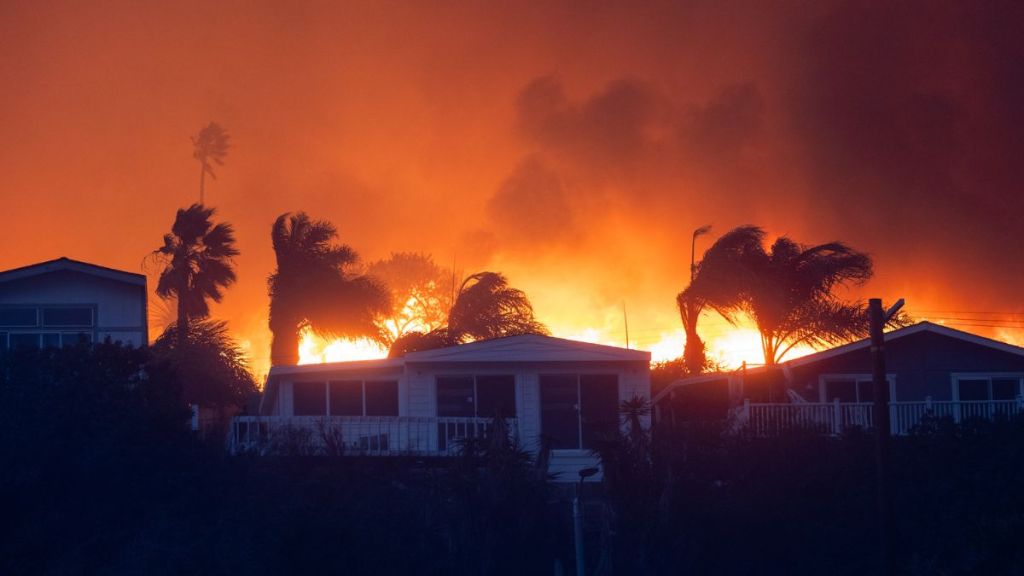 Flames from a brush fire pushed by gusting Santa Ana winds approach homes on January 7, 2025 in Pacific Palisades, Los Angeles, California. A fire in the Pacific Palisades area of Los Angeles has forced some residents to evacuate amid "life-threatening and destructive" winds.